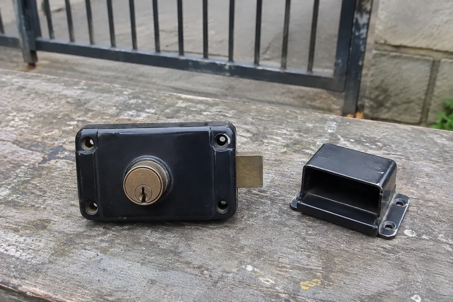 Detached rim gate lock and separate box keeper on an outdoor workbench. — Gate & Building Entry Locks, Oshawa